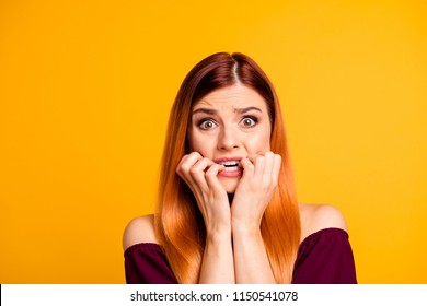 Portrait of red straight-haired attractive cute nice scared worried young girl, biting nails. Isolated over bright vivid yellow background - Shutterstock ID 1150541078
