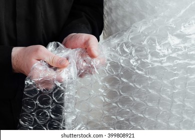 Portrait Of A Red-bearded, Balding Male Brutal. White Isolated Background. A Man In A Black Shirt Pants.  Business Man Funny Relax With Plastic Bubble Wrap.