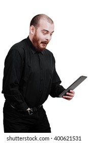 Portrait Of A Red-bearded, Balding Male Brutal. White Isolated Background. Disappointed  Man In A Black Shirt Pants. Looking At Tablet, Ipad.  Surprised Excited. The Hand In The Pants. Masturbation.