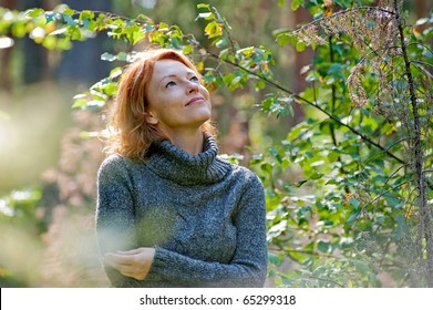 Portrait Of Red-haired Adult Woman In Nature