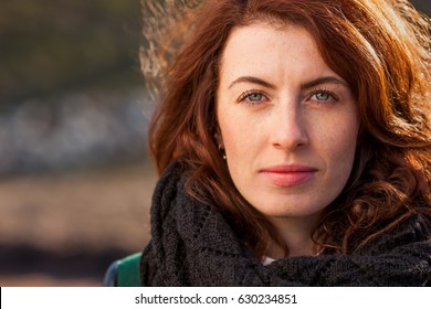 Portrait of a red-haired girl on the street. She looks forward and looks confidently
