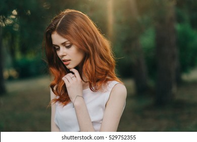 Portrait of red-haired girl in the park in the last rays.