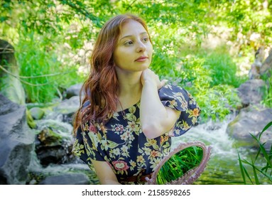 A portrait of redhead Armenian girl sitting sitting by the waterfall