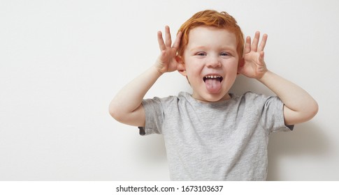 Portrait Of A Redhead Ginger Boy, Child And Toddler Being Silly And Having Fun In Front Of Camera, Showing A Silly Face And Emotions.