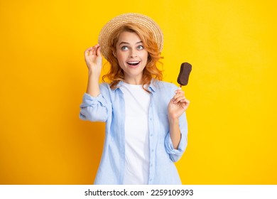 Portrait of redhead girl with chocolate ice cream on yellow background. Curly cheerful woman eating ice cream.