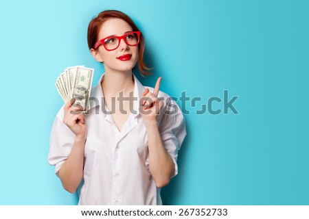 Portrait of redhead women in red glasses with money on blue background