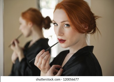 Portrait Of A Redheaded Woman Applying Lip Liner