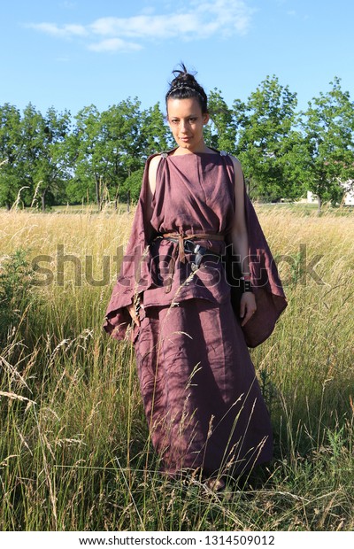 Portrait\
of a reenacting woman clothed in antique roman or greek burgundy\
peplum made from linen and leather\
accessoires