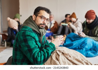 Portrait of refugee hiding in shelter during war or crisis and holding hot drink, copy space