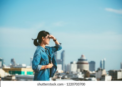 Portrait Of A Relaxed Asian Woman Looking Forward At The Horizon Cityscape In The Background With Her Hand On The Forehead- Copy Space