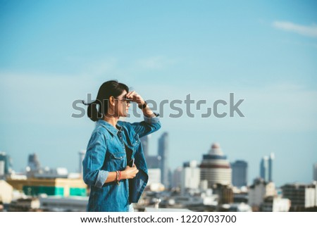 Portrait of a relaxed Asian woman looking forward at the horizon cityscape in the background with her hand on the forehead- copy space