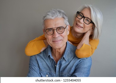  Portrait of relaxed fun senior couple wearing glasses on background                               - Powered by Shutterstock