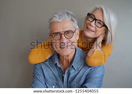  Portrait of relaxed fun senior couple wearing glasses on background                              