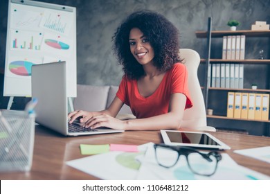 Portrait of representative charming lawyer in casual outfit with beaming smile sitting at desk looking at camera typing on keyboard of laptop using wifi internet