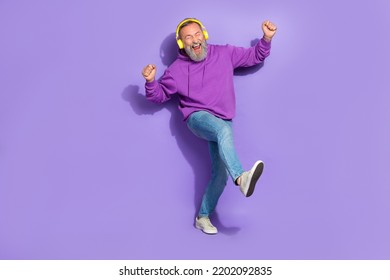 Portrait of retired funny carefree man dressed purple hoodie headphones dancing listen best songs isolated on violet color background - Powered by Shutterstock