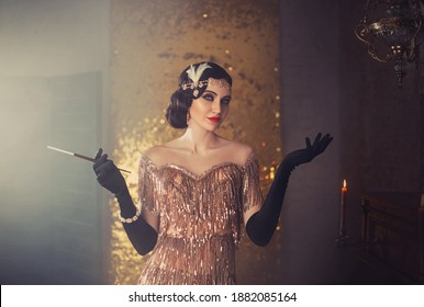 portrait of retro flapper beauty fashion model. Woman holding long slim mouthpiece in hand, cigarette. Party 20s style room full smoke. Gold shiny dress, accessories. Invitation gesture, free space