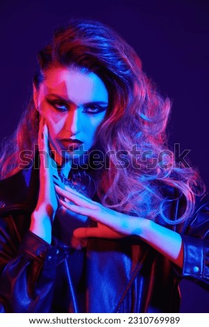 Portrait of a rock star girl with bright glitter makeup and hair in glam rock style in colored stage lighting. Rock accessories. Rock and Pop music.