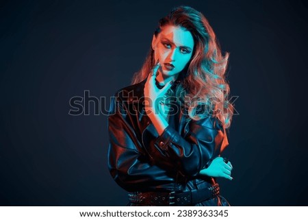Portrait of a rock star girl with bright glitter makeup and hair in glam rock style in colored stage lighting. Rock and Pop music. 