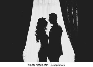 portrait of a romantic couple , silhouette, couple of lovers groom and bride at the window, black and white photography .