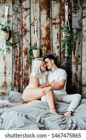 Portrait Of Romantic Couple Sitting On Bed In Bedroom