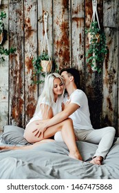 Portrait Of Romantic Couple Sitting On Bed In Bedroom