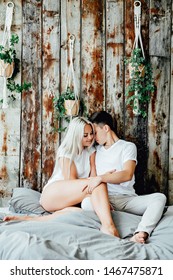 Portrait Of Romantic Couple Sitting On Bed In Bedroom