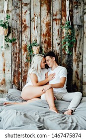 Portrait Of Romantic Couple Sitting On Bed In Bedroom