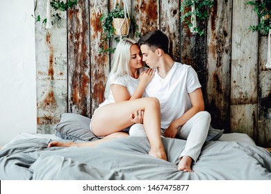 Portrait Of Romantic Couple Sitting On Bed In Bedroom