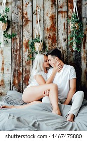 Portrait Of Romantic Couple Sitting On Bed In Bedroom