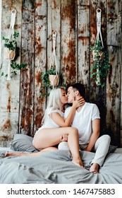 Portrait Of Romantic Couple Sitting On Bed In Bedroom