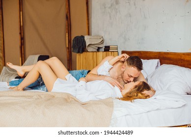 Portrait Of Romantic Couple Sitting On Bed In Bedroom