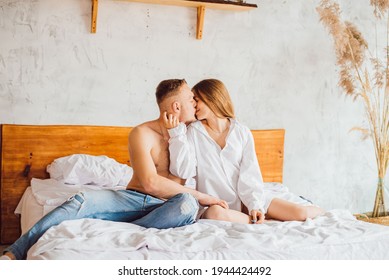 Portrait Of Romantic Couple Sitting On Bed In Bedroom