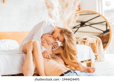 Portrait Of Romantic Couple Sitting On Bed In Bedroom