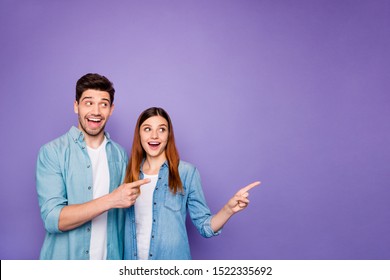 Portrait Of Romantic Excited Couple Of Business People Freelancer Scream Wow Look At Copyspace Point Index Finger Ads Tips Wear Denim Jeans Clothes Isolated Over Violet Purple Color Background