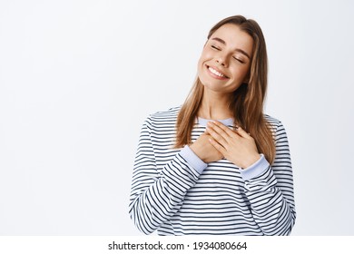 Portrait Of Romantic Happy Woman Close Eyes, Holding Hands On Heart And Daydreaming, Remember Lovely Memory, Having Pure Feelings In Heart, White Background