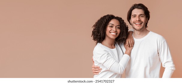 Portrait of romantic multiracial couple embracing, posing together and smiling at camera, standing over yellow background - Powered by Shutterstock