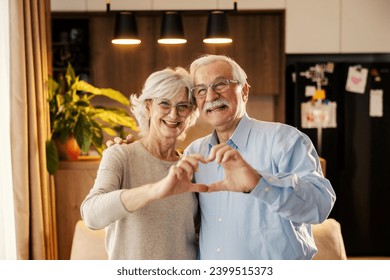 Portrait of a romantic senior couple gesturing heart with hands. - Powered by Shutterstock