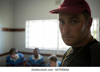 Portrait of rugby coach with team standing in locker room - Powered by Shutterstock