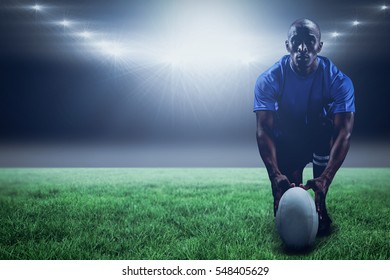 Portrait of rugby player holding ball while kneeling against spotlight and copy space 3d - Powered by Shutterstock