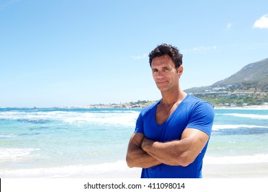 Portrait Of A Rugged Good Looking Man Standing With Arms Crossed At The Beach 