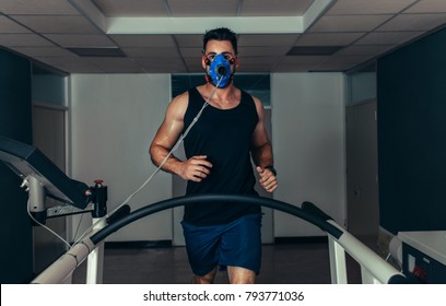 Portrait Of Runner Wearing Mask On Treadmill In Sports Science Laboratory. Sports Man Running On Treadmill And Monitoring His Fitness Performance.