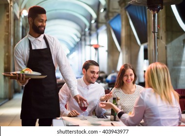 Portrait of russian friends in outside restaurant and black waiter