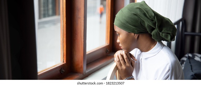 Portrait Of Sad African Young Woman Cancer Patient Fighting With The Sickness, Wearing Head Scarf After Suffering Serious Hair Loss Side Effect Due To Chemotherapy, Concept Of Cancer Awareness