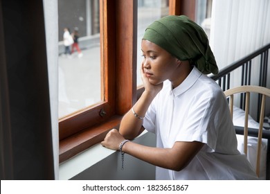 Portrait Of Sad African Young Woman Cancer Patient Fighting With The Sickness, Wearing Head Scarf After Suffering Serious Hair Loss Side Effect Due To Chemotherapy, Concept Of Cancer Awareness