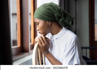Portrait of sad African young woman cancer patient fighting with the sickness, wearing head scarf after suffering serious hair loss side effect due to chemotherapy, concept of cancer awareness