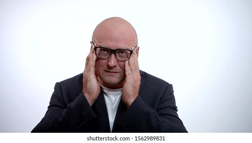 A Portrait Of A Sad Bald Man With Glasses, Wearing A Jacket And A Shirt, He Is In The Studio On A White Background, Rubbing His Hands On The Temples On His Head, Takes Off His Glasses And Looks Up.