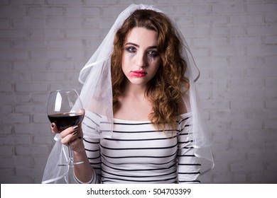 portrait of sad bride crying and drinking red wine