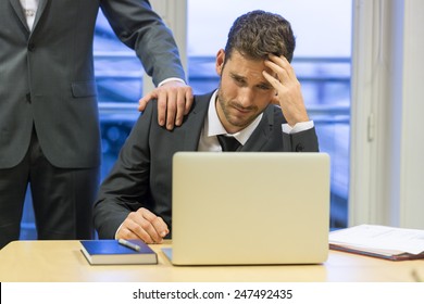 Portrait Of Sad Businessman With Her Boss At Background. Hand On Shoulder