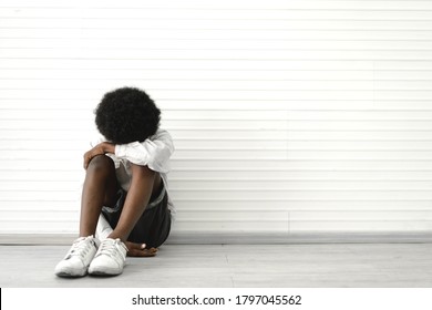 Portrait of sad depressed black african american cute little boy child alone sitting on floor at home