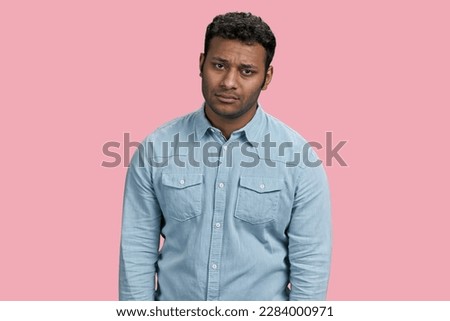Portrait of sad depressive young indian man. Isolated on pink.